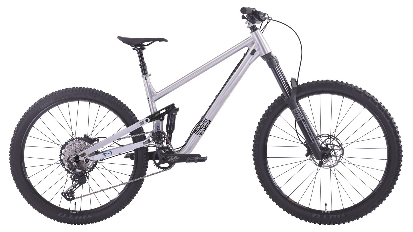 A silver full-suspension mountain bike with black knobby tires, a black saddle, and a black front fork, shown from a side profile on a white background.